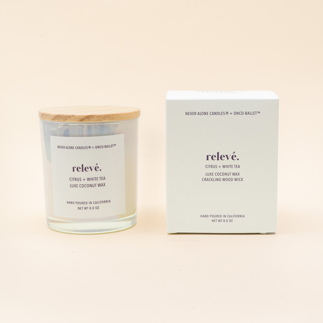 A clear glass jar candle with a light wood lid and a white label reading relevé. sits beside its matching white product box on a warm off-white background.