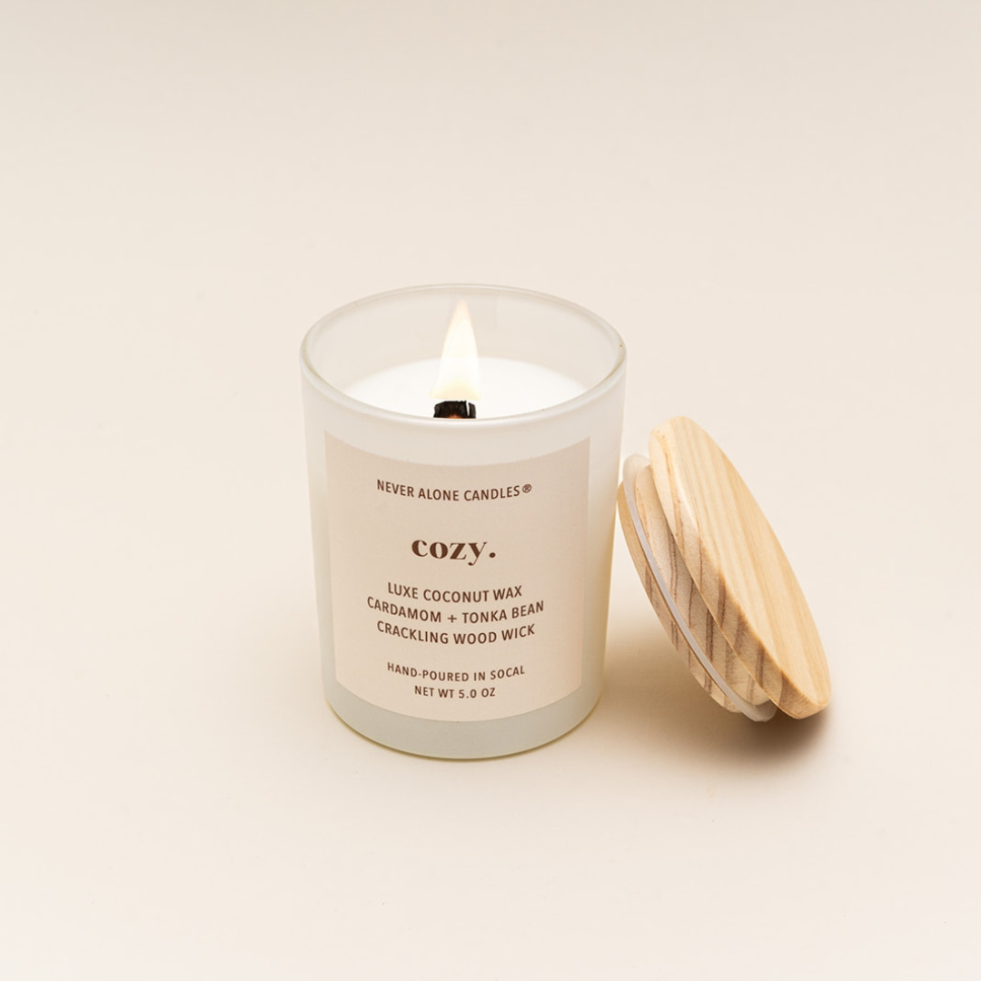 Lit candle made with natural coconut wax, hand-poured in small batches, featuring a long-lasting crackling wood wick and a fragrant blend of cardamom and tonka bean